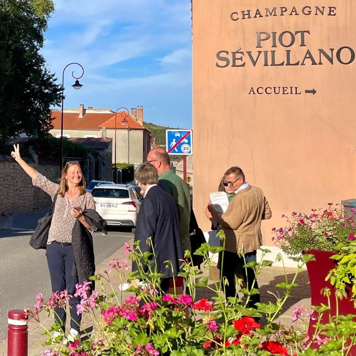 Louise Søborg på besøg hos Champagne Piot-Sévillano med gæster, glad med V-tegn, stå ved vejen, indgang til champagnehuset