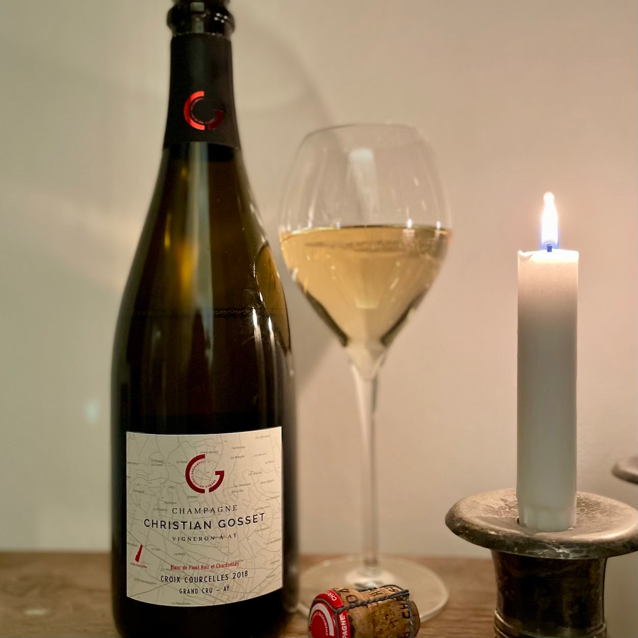 Champagneflaske og champagneglas med sterinlys tændt og champagneprop, Champagne Christian Gosset, Croix Courcelles 2018, Grand Cru