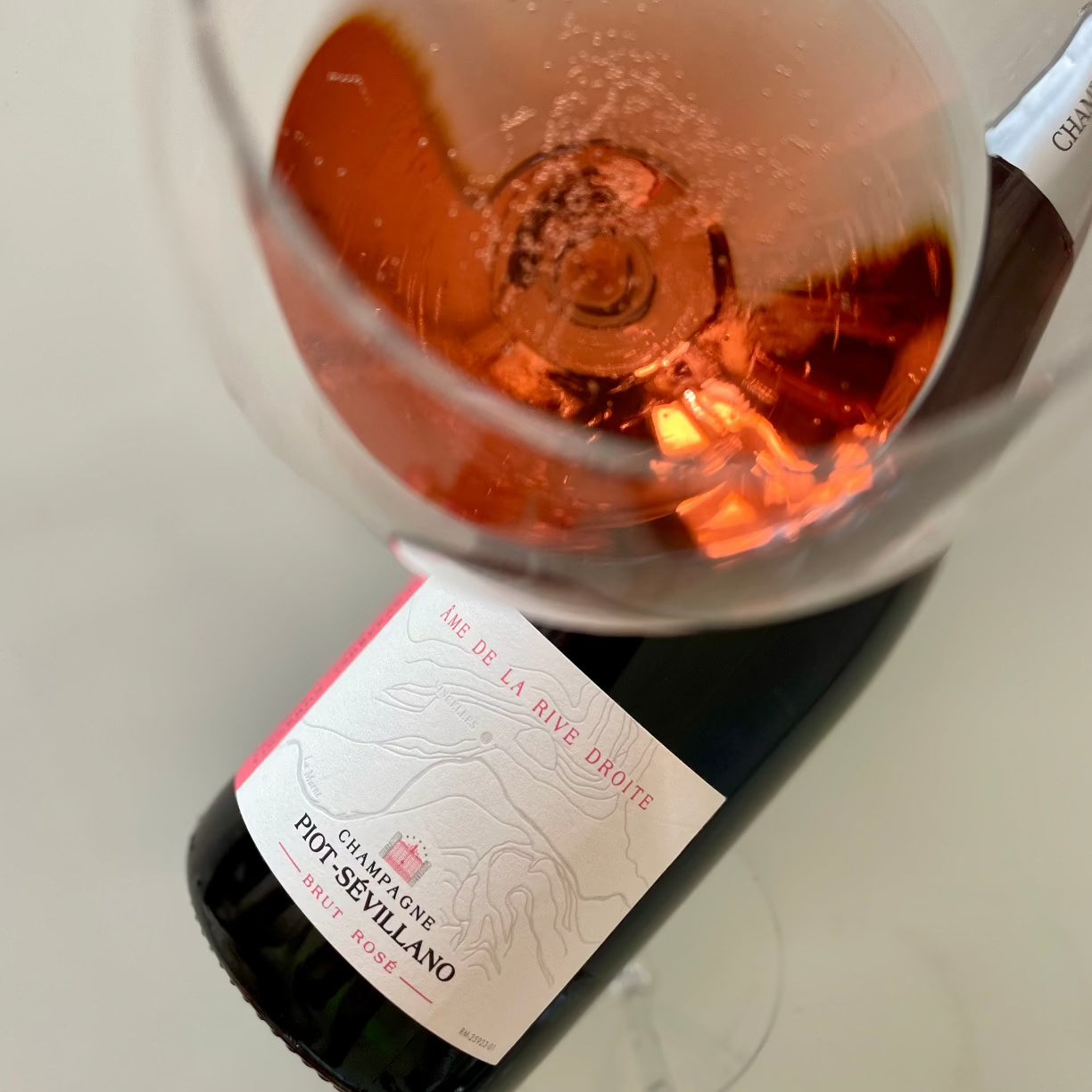 Champagne flaske ligger på bord, tæt på champagneglas med rosé champagne set oppefra, Champagne Piot-Sévillano, Âme de la Rive Droite, Brut Rosé