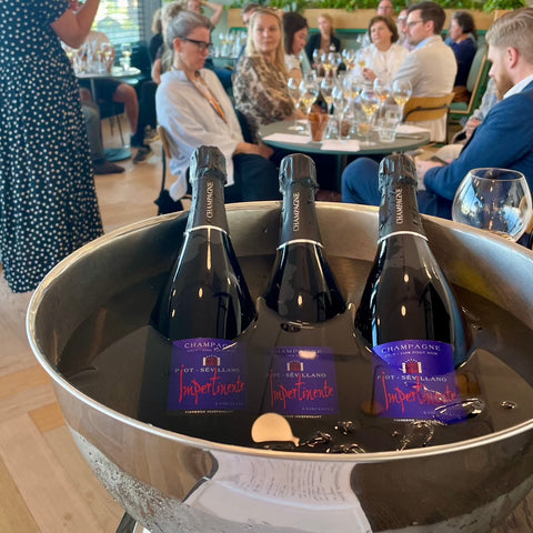 3 flasker champagne i bowle med isvand, i baggrunden ses mange mennesker til champagnesmagning med mange champagneglas, Champagne Piot-Sévillano, Impertinante, 100% Pinot Noir