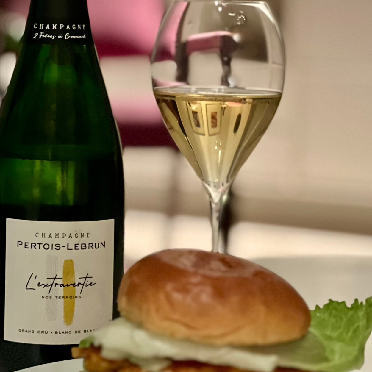 Champagne flaske på bord med burger og et champagneglas fyldt med champagne, Champagne Pertois-Lebrun, L'Extravertie, Grand Cru, Blanc de Blancs